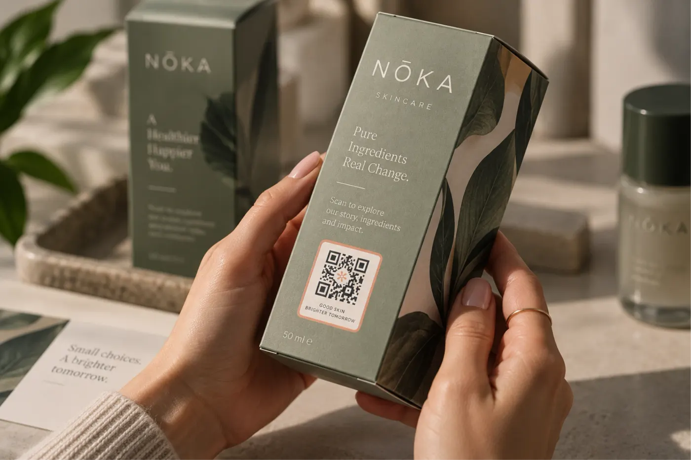 Hands holding a NŌKA skincare box with a branded QR code printed on the pack